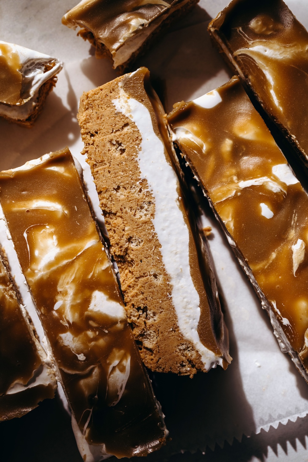 Close up of sliced no bake fluffernutter protein bars with a sunbutter base, marshmallow fluff layer, and glossy chocolate coating