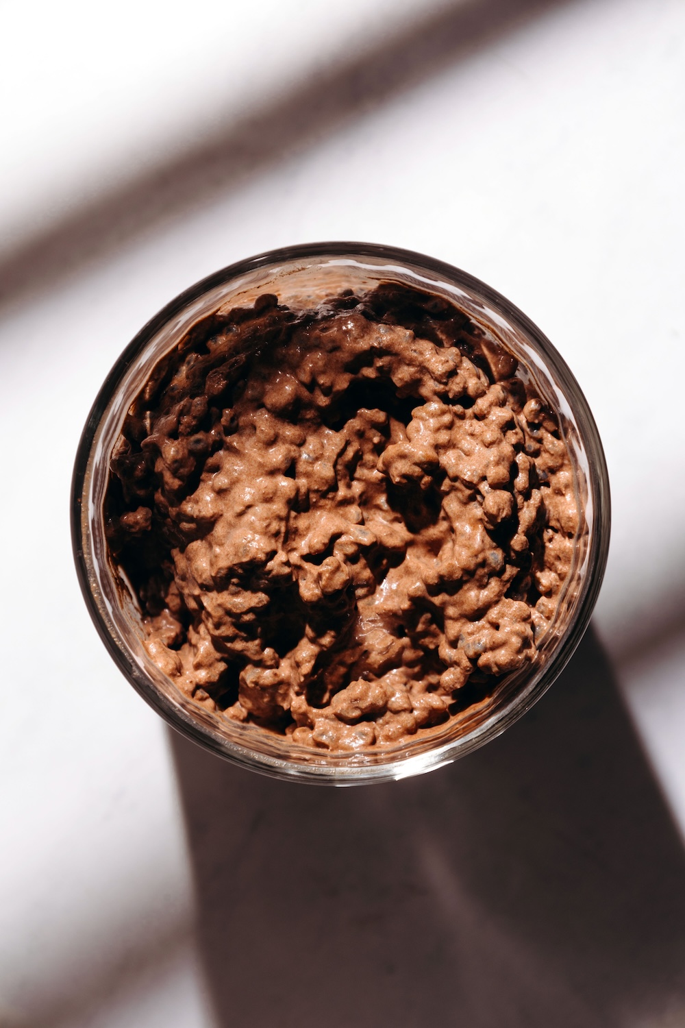 Overhead view of chocolate basil seed pudding without toppings in a glass cup.
