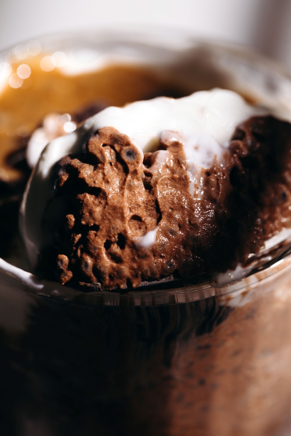 Close-up of thick, creamy chocolate basil seed pudding with a dollop of yogurt on top, served in a clear glass bowl.