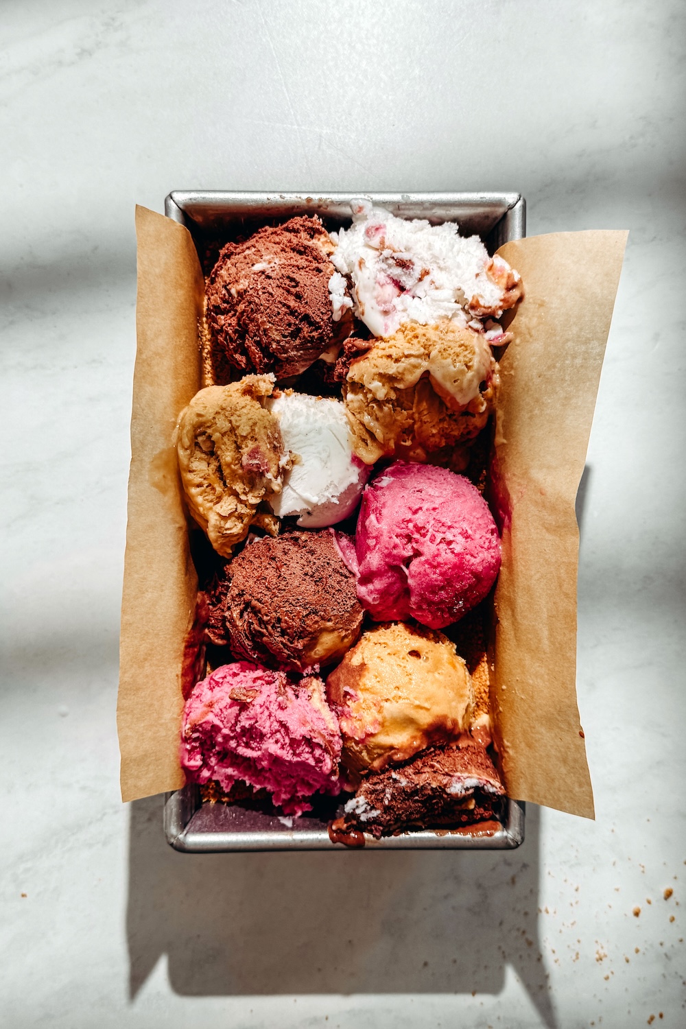 Scoops of dairy-free ice cream in multiple flavors filling a parchment-lined loaf pan