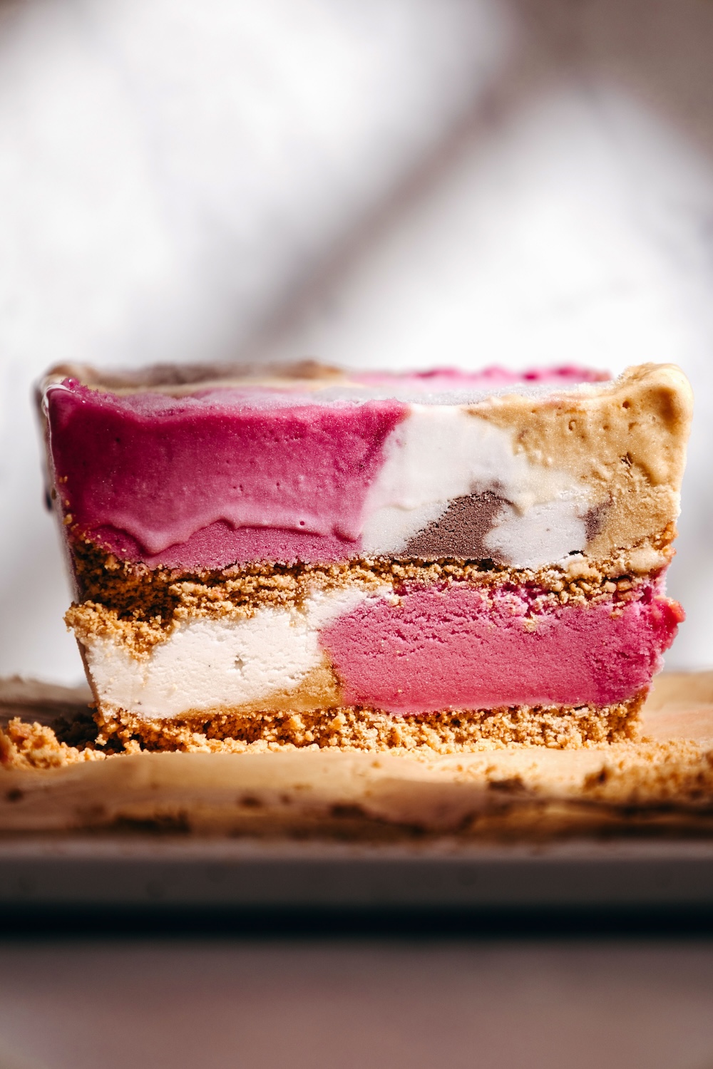Cross-section of a gluten-free loaf pan ice cream cake showing layers of blueberry, vanilla, and chocolate ice cream with a sugar cone crust