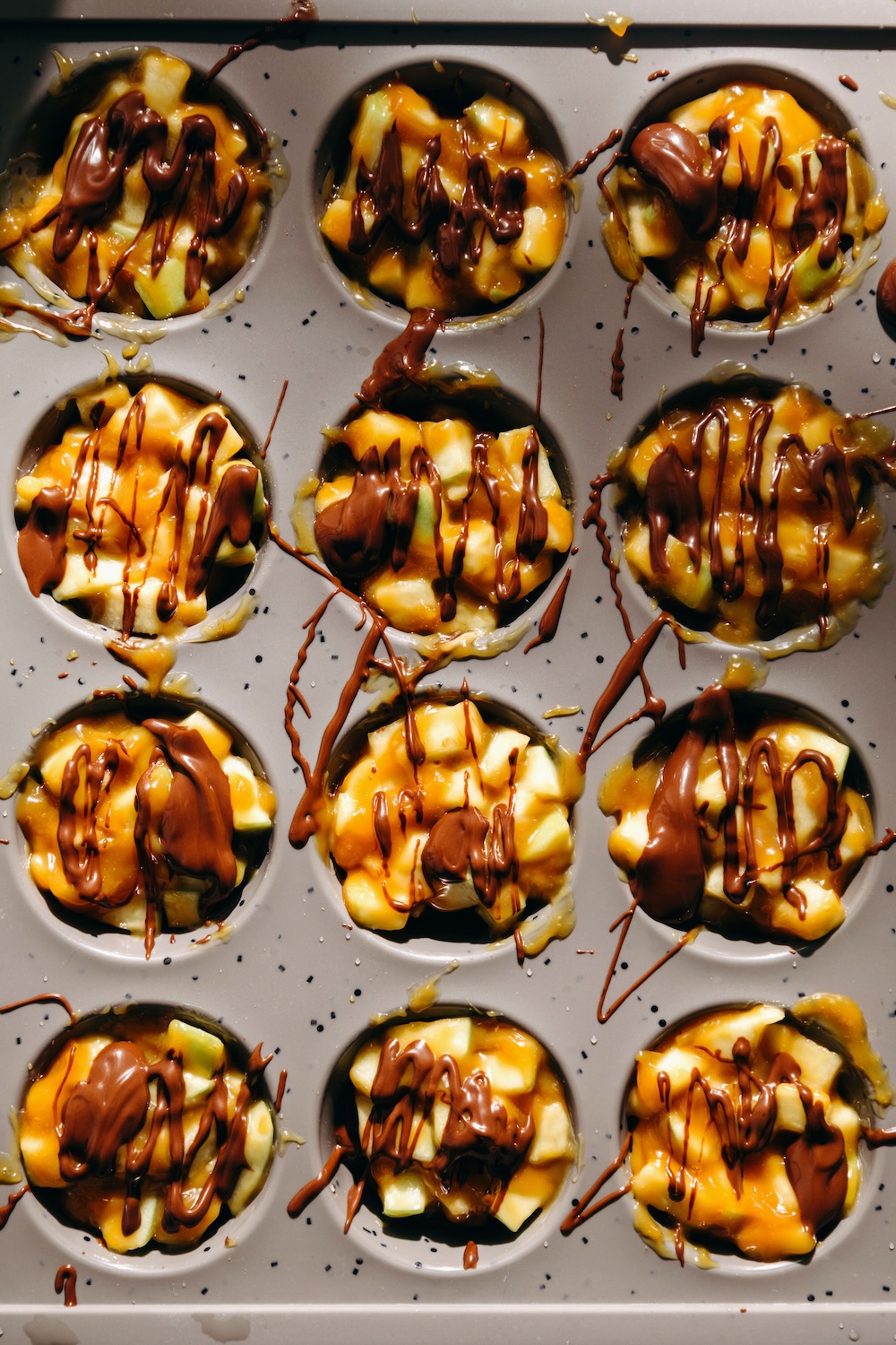 mini muffin pan with chocolate drizzle added over caramel apple pretzel bites