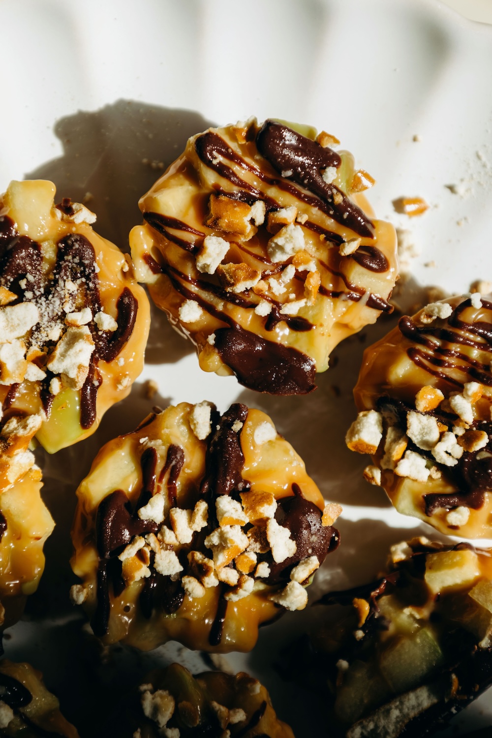 close up of caramel apple pretzel bites with chocolate drizzle and pretzel crumbs