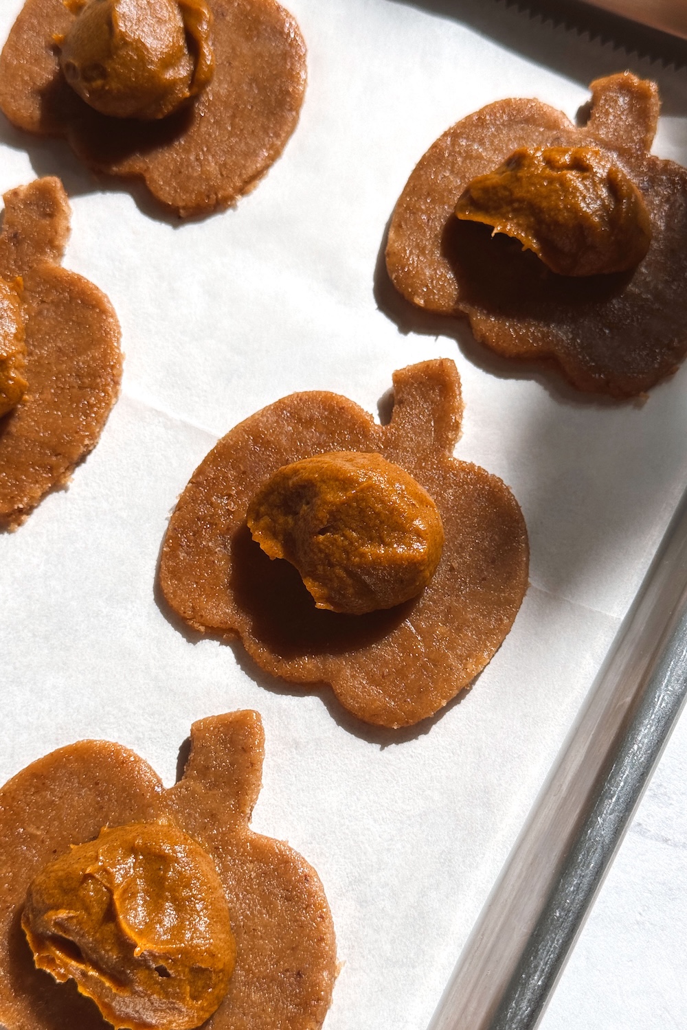 Scoops of pumpkin pie filling on pumpkin-shaped cutouts of gluten-free dough.