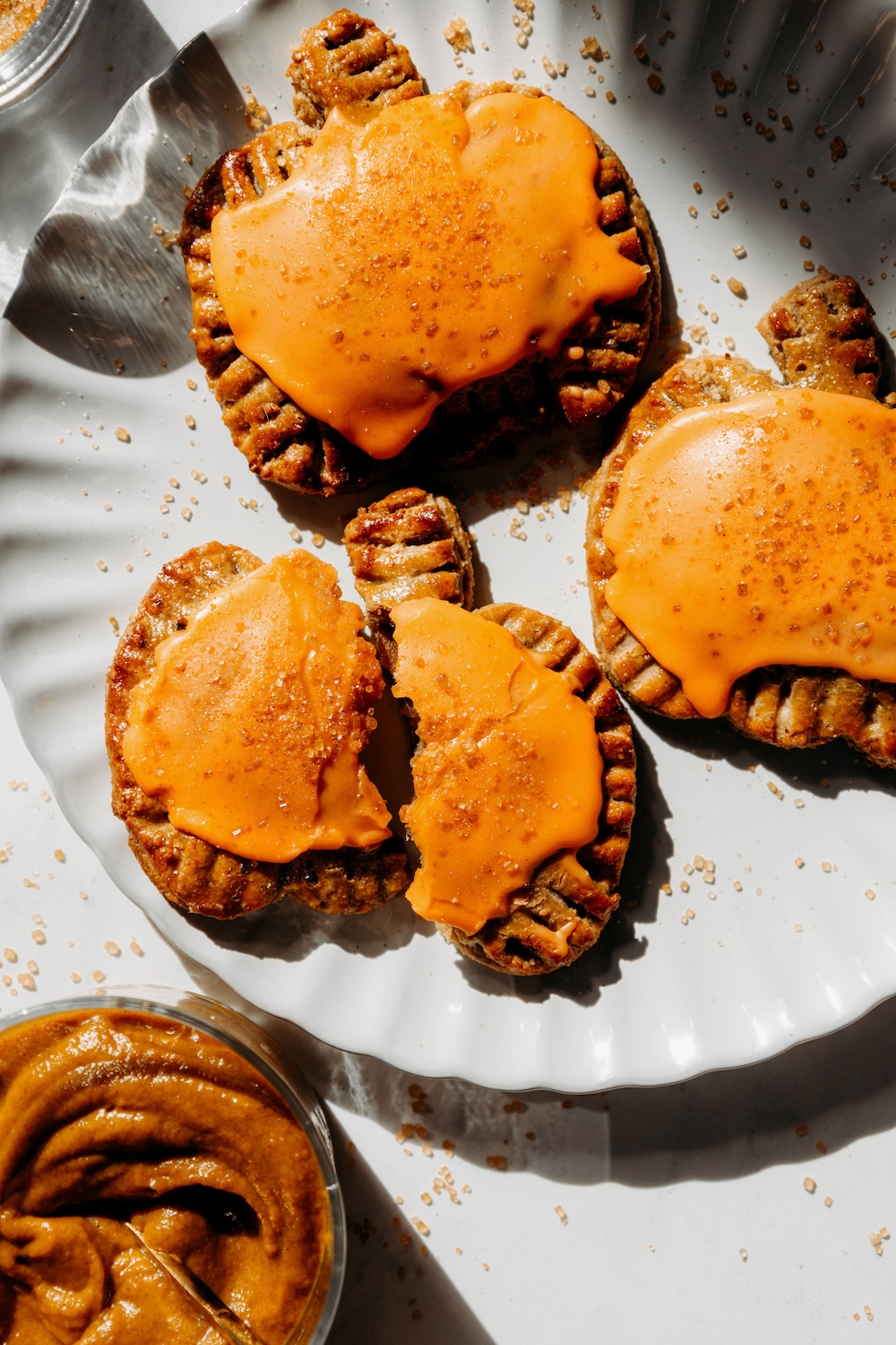 Glazed pumpkin pie pop tarts on a white plate, with one broken in half.